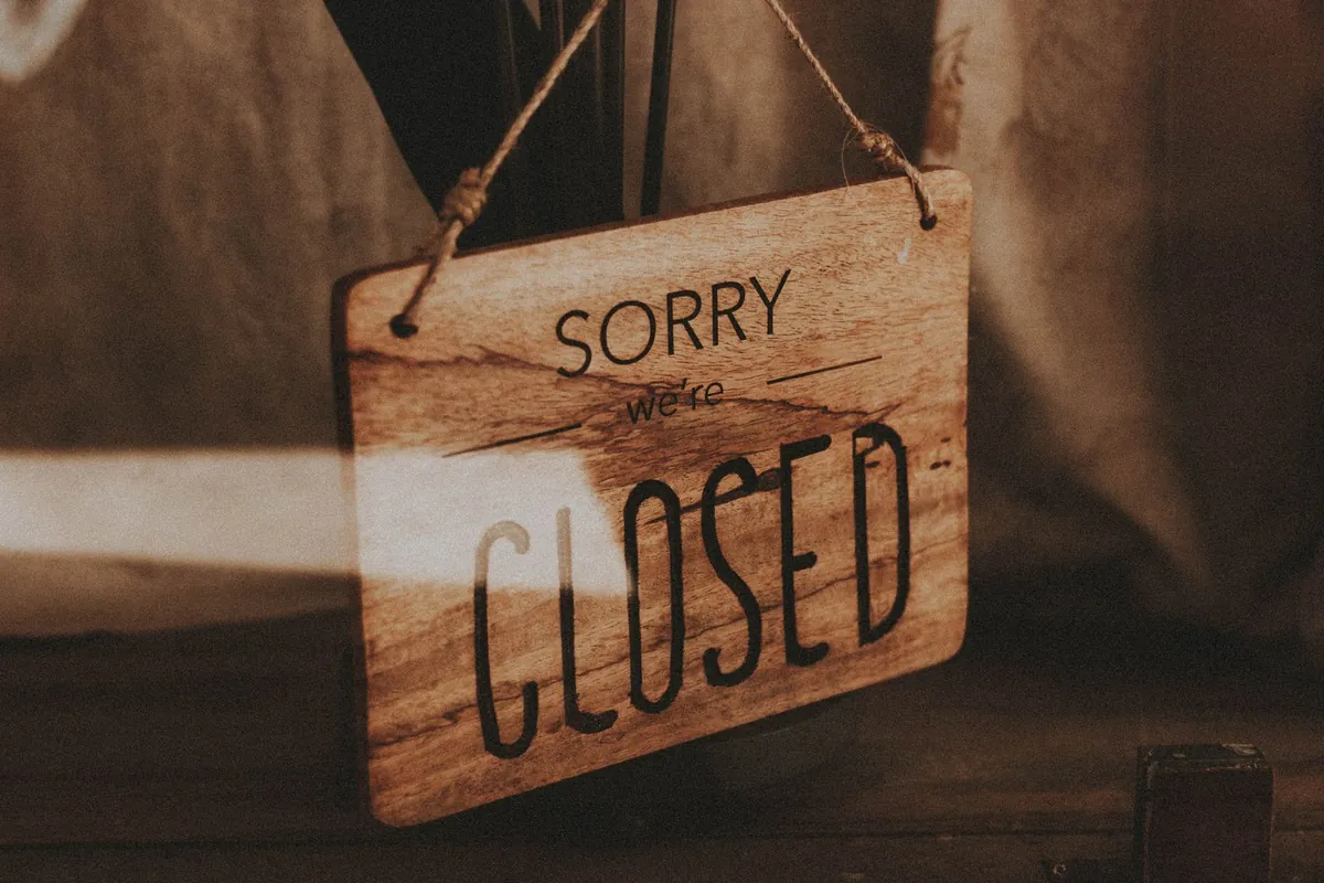 A rustic wooden sign reading Sorry we're closed hanging in a doorway